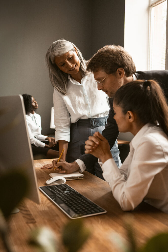 International business team work together. Young man making notes in notebook. Adult female boss in the office. Office collaboration concept